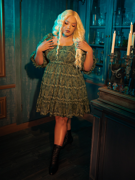Embrace the dark allure of the CRIMSON PEAK™ Allerdale Moth Wallpaper Babydoll Dress. The olive backdrop, rich and earthy, sets the stage for a dance of moths — creatures of the night drawn to the unseen and the unknown. This dress embodies the delicate balance between darkness and light, offering a unique statement piece for those who walk the path less traveled.