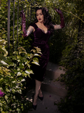 The gothic dress clings and curves, leaving behind a trail of longing and whispers in plum velvet.
