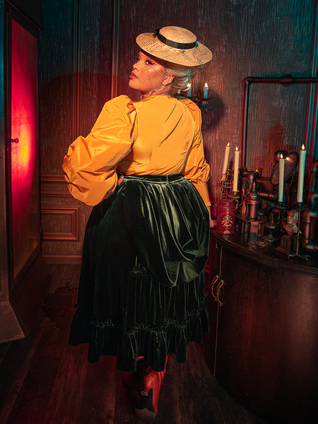 Captivating the essence of gothic elegance, models display the hauntingly gorgeous Victorian Velvet Bustle Skirt in Olive for La Femme en Noir.