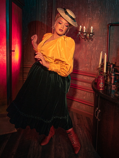 The dark allure of the Victorian Velvet Bustle Skirt in Olive is skillfully portrayed by models showcasing the hauntingly gorgeous design for La Femme en Noir.