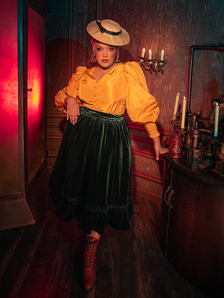 Witness the mysterious charm of the Victorian Velvet Bustle Skirt in Olive as models from La Femme en Noir flaunt its hauntingly gorgeous design.
