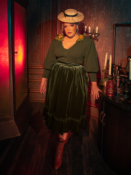 The eerie elegance of the Victorian Velvet Bustle Skirt in Olive is revealed as models flaunt this hauntingly gorgeous piece from the gothic clothing brand La Femme en Noir.