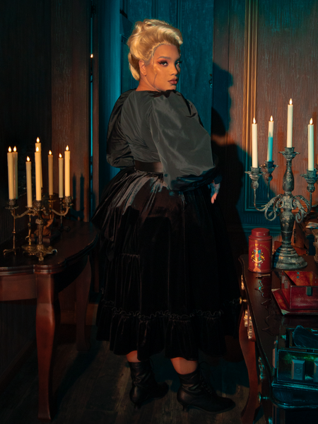 Witness the mysterious charm of the Victorian Velvet Bustle Skirt in Black as models from La Femme en Noir flaunt its hauntingly beautiful design.