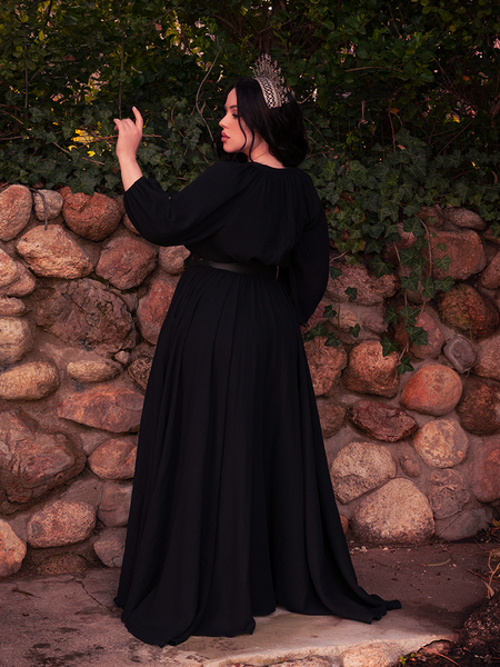 Descending stone steps, the gothic clothing look transforms her into a queen of ruins.