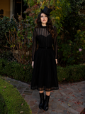 The sweeping skirt glides like a midnight waltz across marble floors, each step an echo of grace and solemnity.