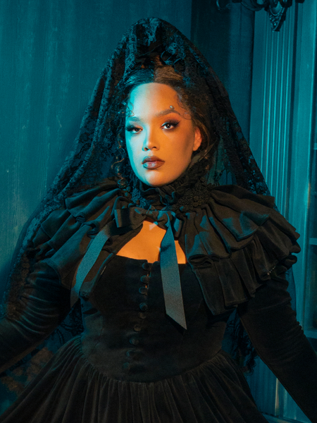 Become a siren of the shadows in this Victorian Mourning Dress. The capelet flutters behind you, a beacon in the dark, calling to those who dare to love amidst the whispers of the night.