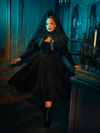 The majesty of mourning is captured in the elegant lines of this Victorian Mourning Dress. The capelet, a crown of fabric, elevates the ensemble, turning grief into a form of beauty that commands respect and evokes empathy.