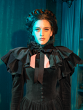 In mourning's fashion, this dress stands as a monument to love everlasting. The capelet, a gentle reminder of the world beyond, drapes the shoulders in a fashion that is both a tribute and a statement, a balance of grief and grace.