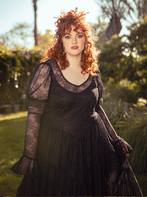 A vision of midnight romance, the Juliet Sheer Lace Maxi Dress in Black drapes the body in ethereal lace, a hauntingly elegant silhouette for moonlit soirees.