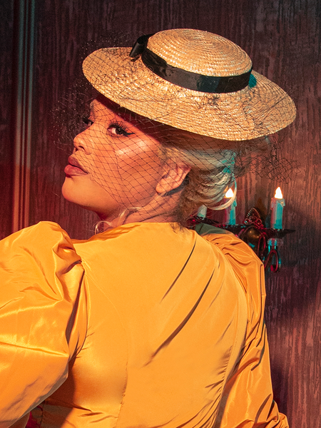 Unveiling an air of gothic mystique, a female model captures attention while presenting the Wicket Tilt Hat with Black Veil from La Femme en Noir, the gothic clothing brand synonymous with enigmatic style.