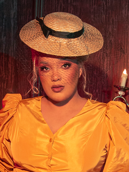 The ethereal beauty of a female gothic model is heightened as she showcases the Wicket Tilt Hat with Black Veil from La Femme en Noir, epitomizing the brand's unique fusion of gothic fashion and enchanting allure.