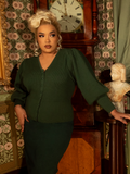 A nod to Victorian refinement, this fitted knit cardigan in hunter green is adorned with elegant pleating and ornate buttons, creating a timelessly polished silhouette.