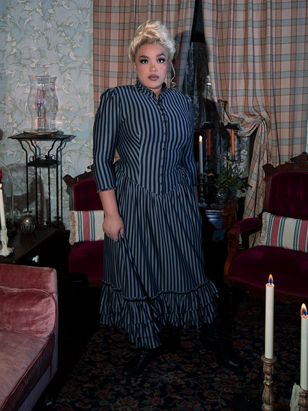 The Victorian Dress in Black and Gray Stripes is a masterpiece of vintage fashion, featuring bold stripes, delicate lace trim, and a structured bodice that enhances its darkly romantic appeal.