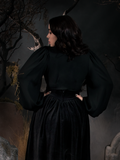 Rachel turned away from the camera to show off the back of the Georgette Wrap Top in Black.