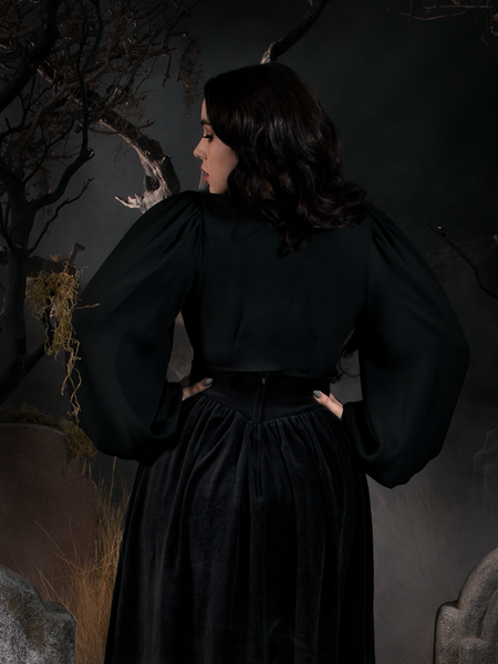Rachel turned away from the camera to show off the back of the Georgette Wrap Top in Black.