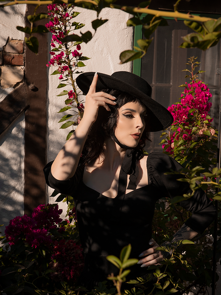 Raven haired model looks off camera while tilting her Bolero Hat in Black to the side.