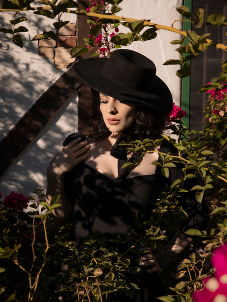 Goth model wears the Bolero Hat in Black to compliment her black goth style dress.