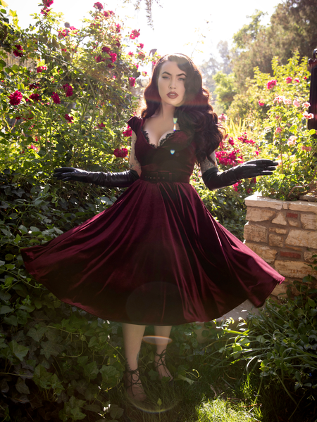 Micheline Pitt looks dazzling and she twirls in the Baudelaire Swing Dress in Oxblood.