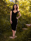 Striking a post with one hand on her hip, Stephanie wears the sexy Baudelaire Wiggle Dress in Black.
