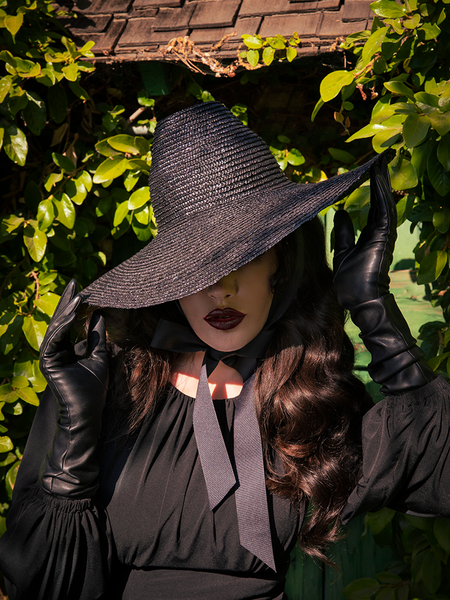 Micheline Pitt adjusting the brim of her Cottage Witch Hat in Black.