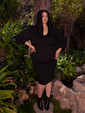 Amidst the breathtaking beauty of a wooded forest area, a stunning brunette model effortlessly flaunts the Black Dark Forest Blouse. Indulge in the gothic elegance of La Femme en Noir.