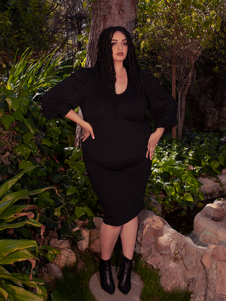 Amidst the breathtaking beauty of a wooded forest area, a stunning brunette model effortlessly flaunts the Black Dark Forest Blouse. Indulge in the gothic elegance of La Femme en Noir.