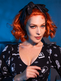 Fire red haired model wearing the BEETLEJUICE™ Delia Glove Headband from goth glamour clothing brand La Femme en Noir.