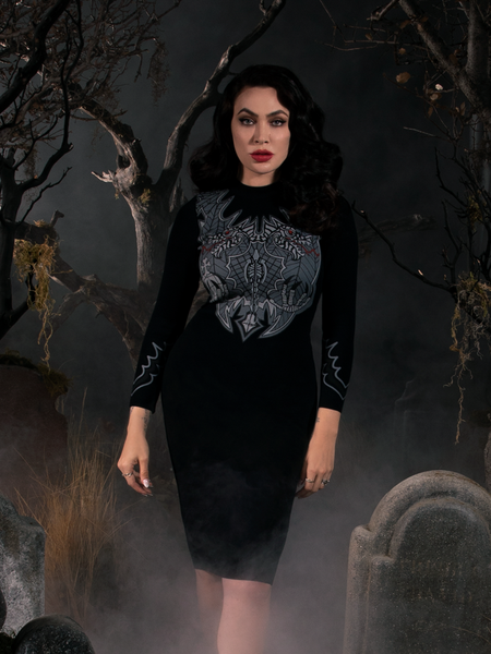 Micheline Pitt wearing the Sleepy Hollow Hessian Dress in Black while standing in a foggy graveyard.