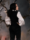 Facing away from the camera, Micheline Pitt subtly looks over her shoulder while modeling the Victorian Blouse in Ivory.