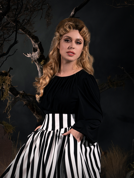 Linda standing with her hands in her pockets while modeling the Salem Top in Black.