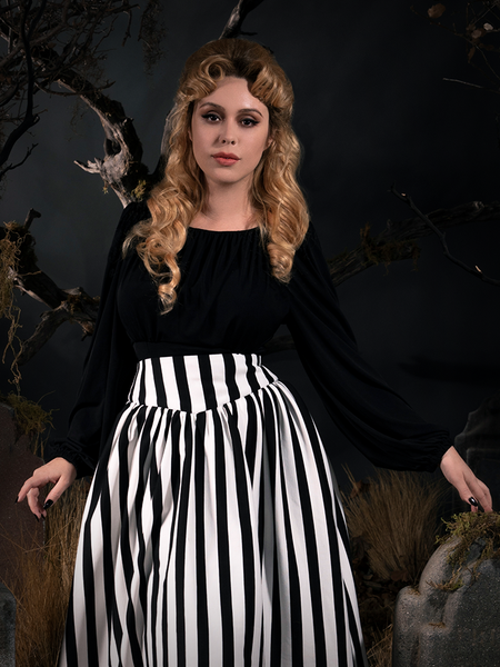 Linda with her hand resting on a tombstone while in the Salem Top in Black from gothic vintage clothing retailer La Femme en Noir.