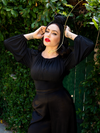 Micheline Pitt posing in her garden with an all gothic retro outfit including the Salem Top in Black.