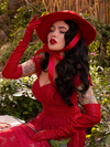 Micheline Pitt sitting in a garden wearing the Southern Gothic Bustier Top in Crimson.