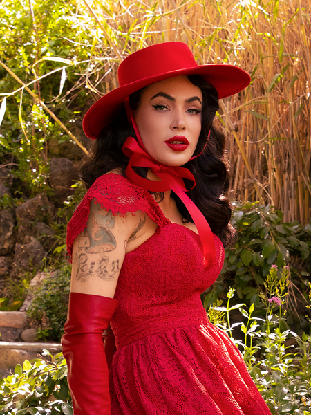 Waist level picture of Micheline Pitt turning to the left to look into the camera to show off her all crimson goth clothing outfit.