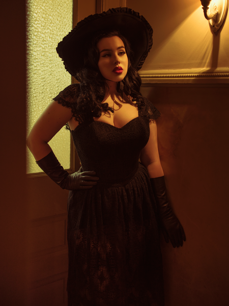 Rachel stands in a dimly lit hallway while modeling the Southern Gothic bustier top in black.