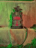 A full length product shot of the BEETLEJUICE™ Tombstone Crossbody Bag sitting on mossy steps.