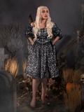 With her hands in her pockets, Micheline looks like a gothic vision in the Sleepy Hollow™ Lady Van Tassel Guipire Lace Dress by La Femme En Noir.