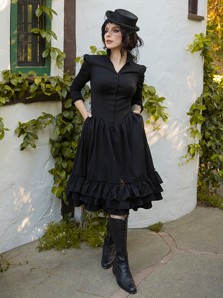 Model tucks her hands into the side pockets of the Victorian Dress in Black.