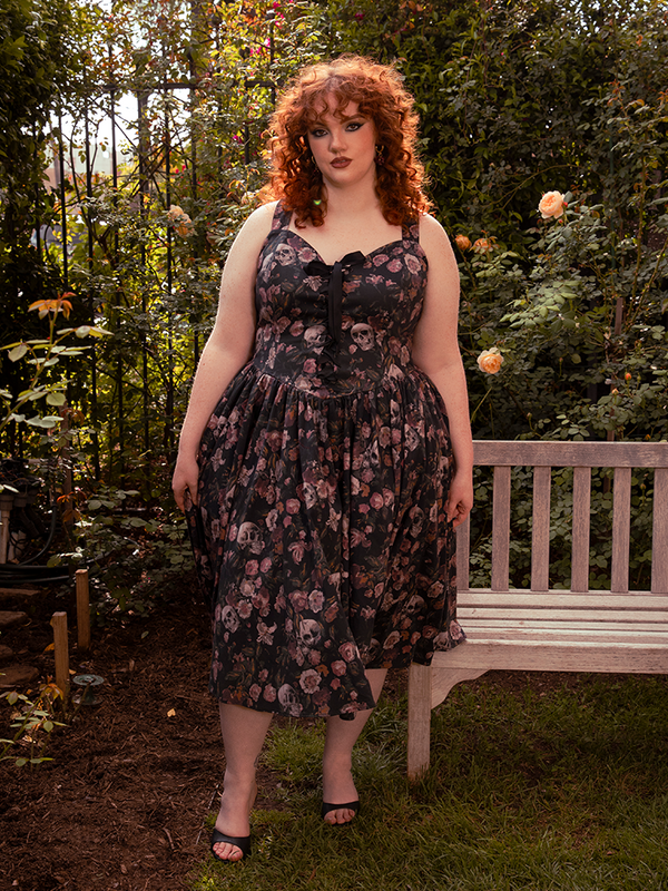 The dark wall of foliage frames her like a living painting—Ambrosia’s haunted florals stealing the scene.