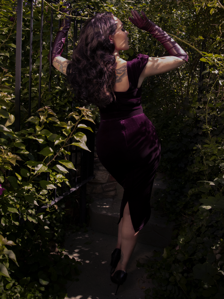 In the mirror, she wears this gothic dress like a vow—plum silk, sin, and a promise to never be forgotten.
