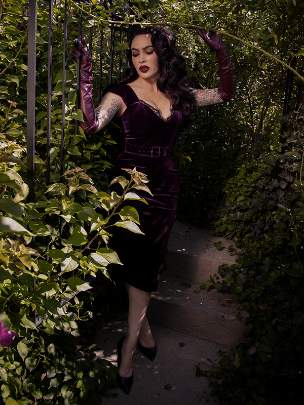The gothic dress clings and curves, leaving behind a trail of longing and whispers in plum velvet.