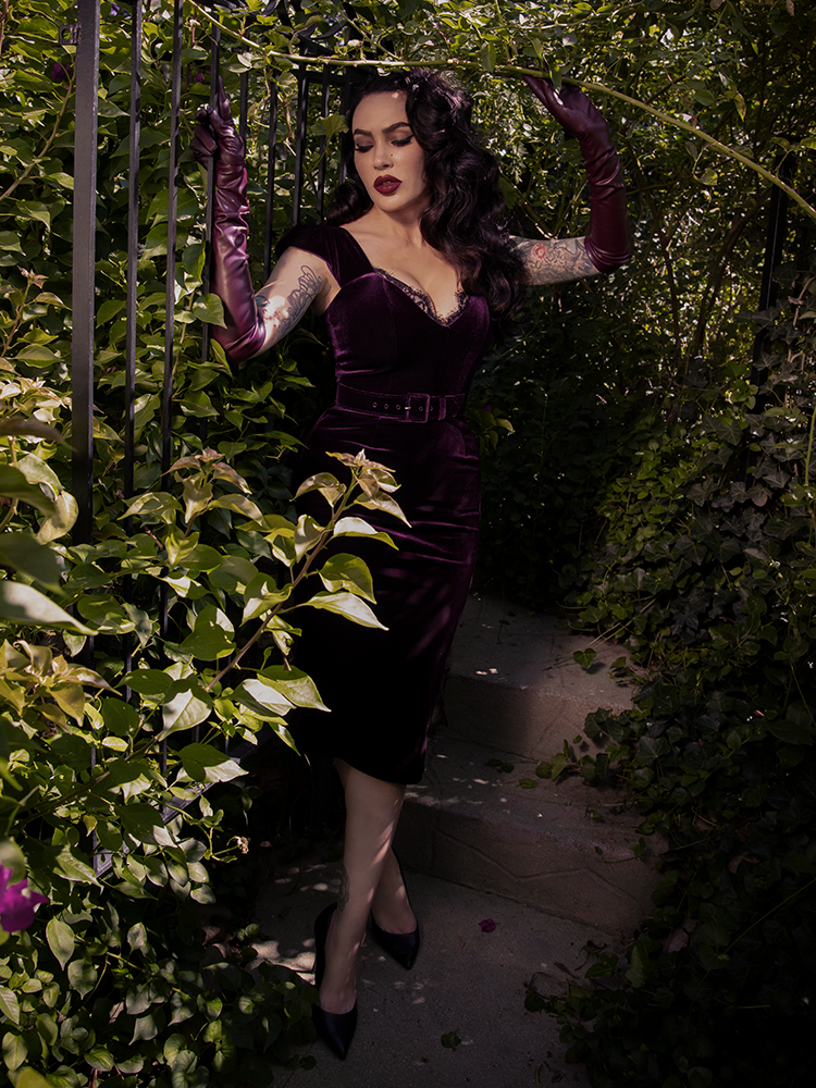 The gothic dress clings and curves, leaving behind a trail of longing and whispers in plum velvet.