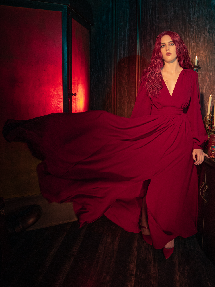 A low-angle shot of the crimson Belladonna dress flowing in the wind, capturing the "Crimson Peak" inspired gothic romance and the rich, saturated red of the heavy georgette fabric.