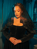 Embodying a mood of introspection, the Gothic female model highlights the Black Veil with Embroidered Lace Trim from La Femme en Noir, revealing a series of pensive poses that enhance the gothic allure of the clothing brand.