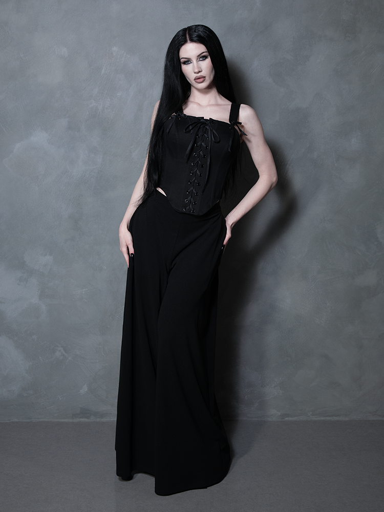 Capturing the dark romanticism of Whimsigoth fashion, a female model wears a tailored black cotton sateen corset.
