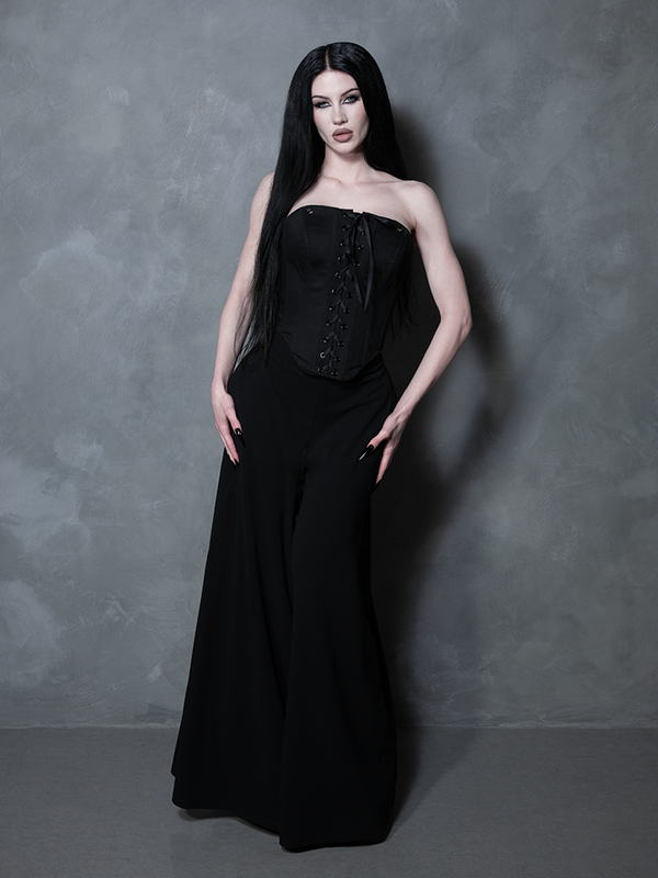 A female model channels romantic moodiness in an essential piece of gothic clothing, wearing a structured black sateen corset.