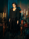 The haunting beauty of the Victorian Velvet Bustle Skirt in Black comes to life as models show it off for La Femme en Noir, the renowned gothic clothing brand.