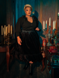The eerie elegance of the Victorian Velvet Bustle Skirt in Black is revealed as models flaunt this hauntingly beautiful piece from the gothic clothing brand La Femme en Noir.