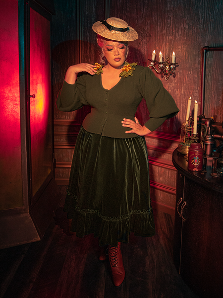 Step into the shadows with models showcasing the hauntingly gorgeous Victorian Velvet Bustle Skirt in Olive, a masterpiece from the gothic clothing brand La Femme en Noir.