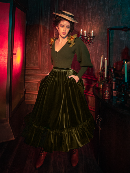 Embrace the dark elegance with models presenting the hauntingly gorgeous Victorian Velvet Bustle Skirt in Olive from the gothic clothing brand La Femme en Noir.